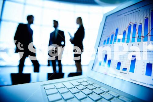 Financial Document In Laptop On Background Of Three Business Partners Interacting